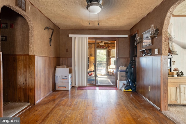 entryway featuring wooden walls, wainscoting, a textured ceiling, and hardwood / wood-style flooring