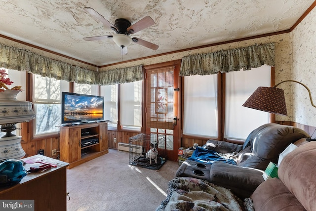 living room with wallpapered walls, a ceiling fan, light colored carpet, crown molding, and a baseboard heating unit