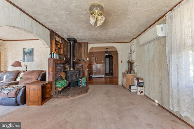 living area featuring carpet floors, arched walkways, a wall unit AC, crown molding, and a wood stove