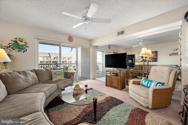 carpeted living area featuring visible vents, a textured ceiling, and ceiling fan