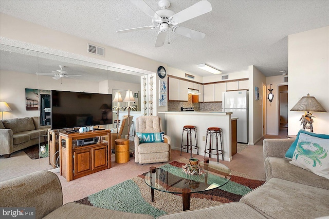 living area featuring visible vents, light carpet, a textured ceiling, and a ceiling fan