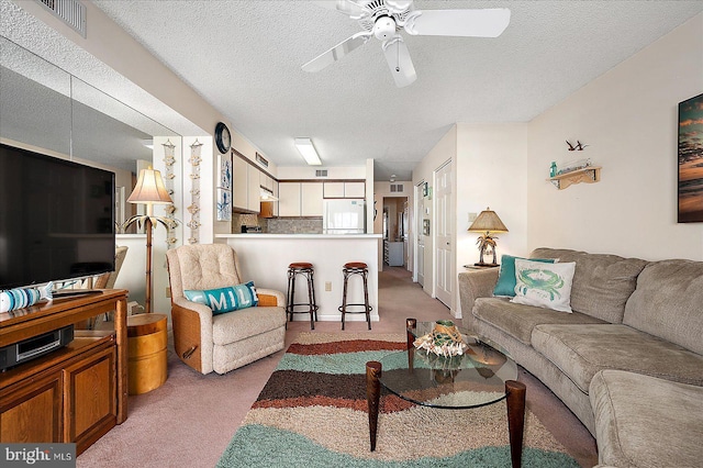 living room with light colored carpet, ceiling fan, and a textured ceiling