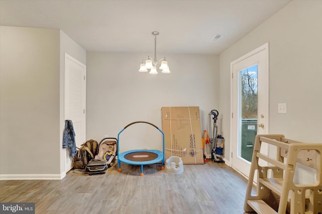 recreation room with baseboards, wood finished floors, visible vents, and an inviting chandelier