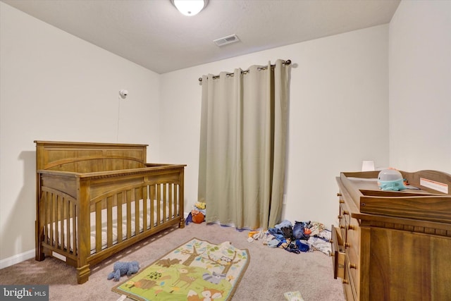 carpeted bedroom with a nursery area, baseboards, and visible vents