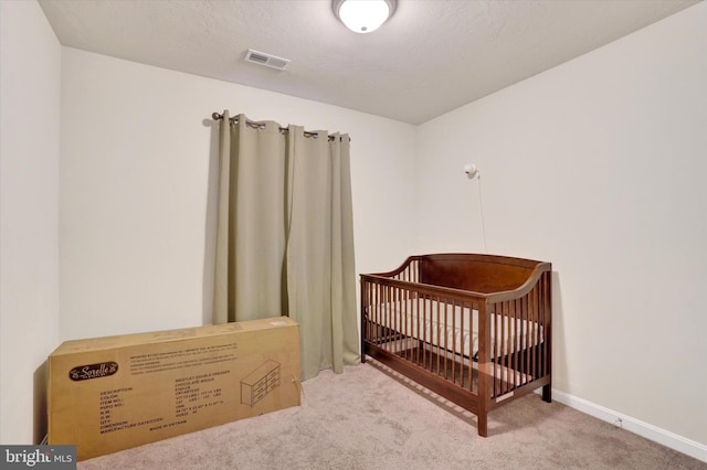 carpeted bedroom featuring a nursery area, visible vents, and baseboards