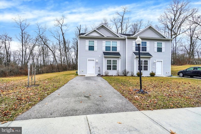 traditional-style house featuring aphalt driveway and a front lawn