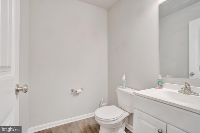 bathroom with baseboards, vanity, toilet, and wood finished floors