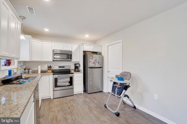 kitchen featuring appliances with stainless steel finishes, light wood-type flooring, visible vents, and white cabinetry