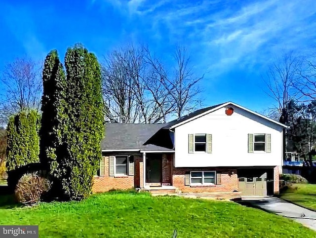 split level home featuring a garage, concrete driveway, brick siding, and a front lawn