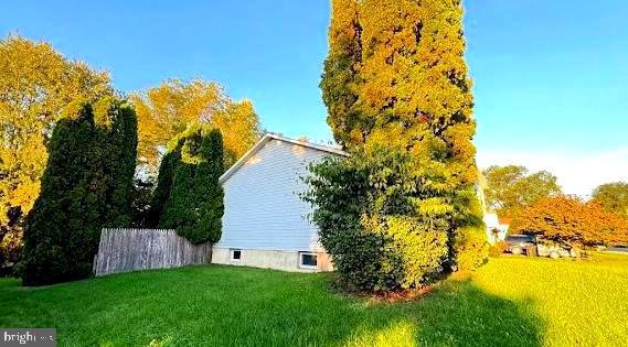 view of side of home with a lawn and fence