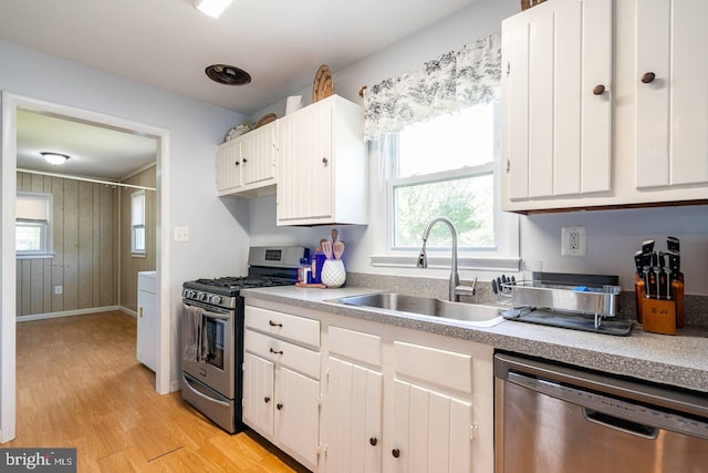 kitchen with appliances with stainless steel finishes, light wood-type flooring, light countertops, and a sink