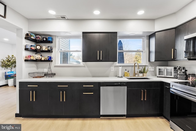 kitchen featuring a sink, appliances with stainless steel finishes, and dark cabinetry