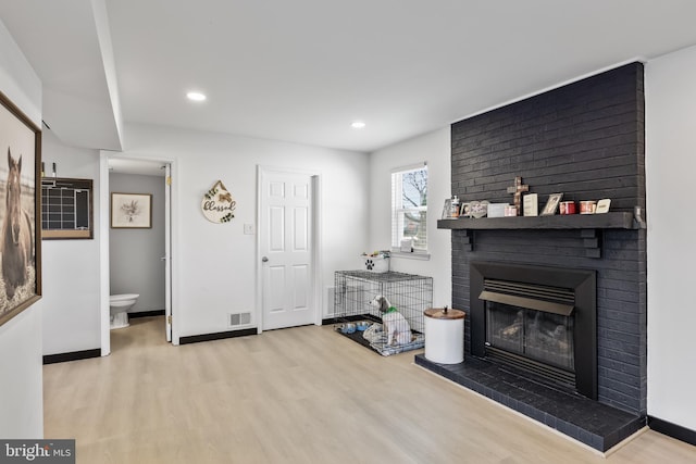 living room featuring visible vents, a brick fireplace, baseboards, recessed lighting, and wood finished floors