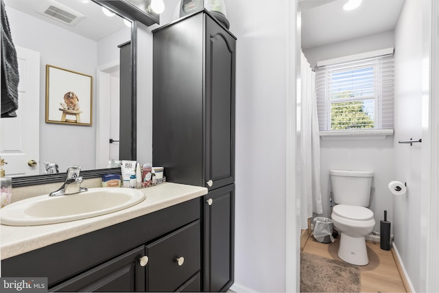 full bathroom with visible vents, baseboards, toilet, wood finished floors, and vanity