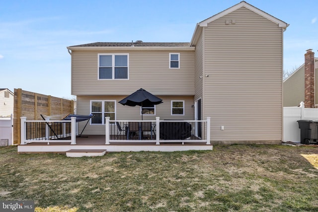 back of house with a lawn, a deck, and fence