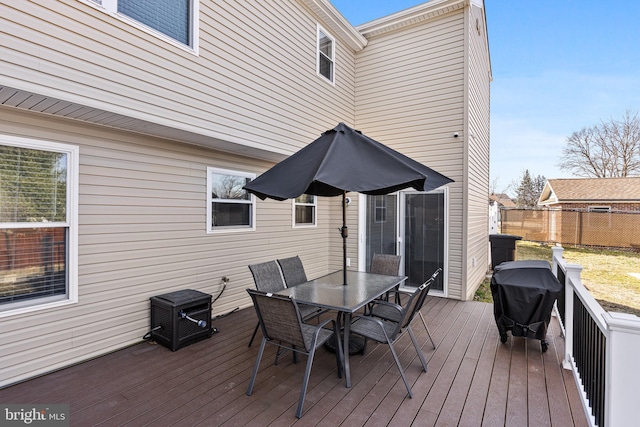 deck with outdoor dining area, grilling area, and fence