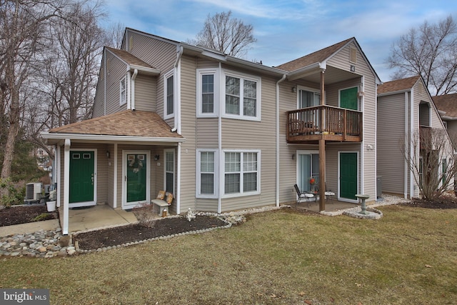 rear view of property featuring a lawn, a patio, a balcony, roof with shingles, and central AC