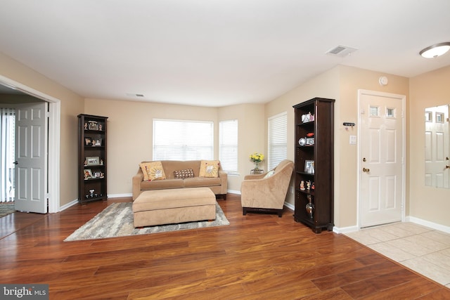 living area with baseboards, visible vents, and wood finished floors