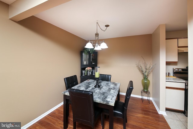 dining area featuring an inviting chandelier, baseboards, and wood finished floors