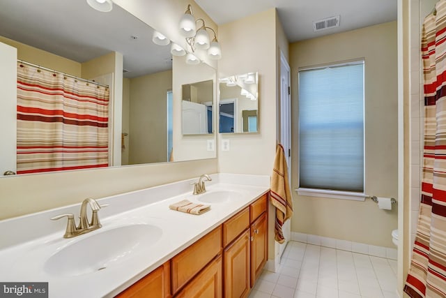 full bath featuring a sink, visible vents, baseboards, and double vanity