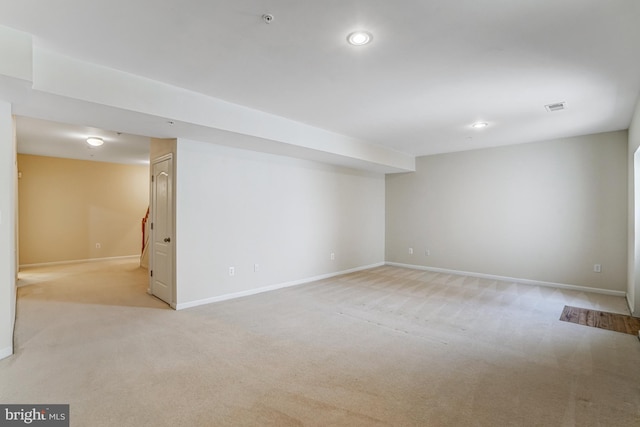 finished below grade area featuring visible vents, recessed lighting, baseboards, and light carpet