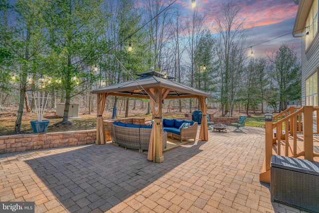 patio terrace at dusk featuring a gazebo, area for grilling, and an outdoor living space with a fire pit