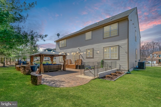 back of property at dusk with a gazebo, cooling unit, a lawn, and a patio area