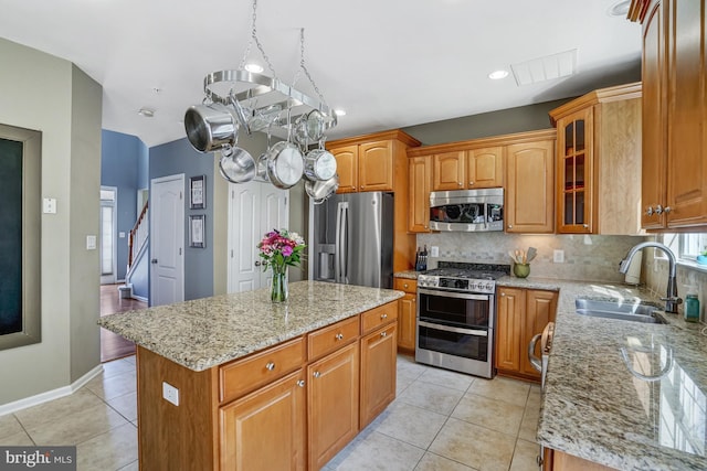 kitchen featuring light tile patterned floors, light stone countertops, a sink, decorative backsplash, and stainless steel appliances