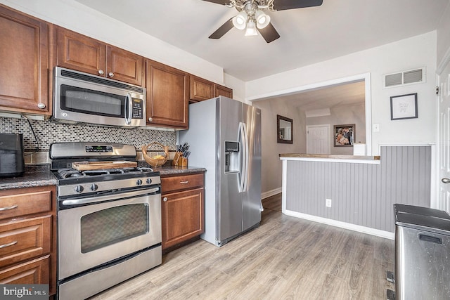 kitchen featuring brown cabinets, dark countertops, visible vents, appliances with stainless steel finishes, and light wood-type flooring