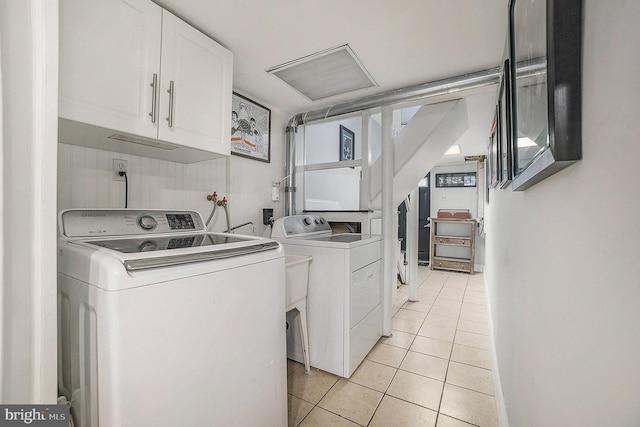 clothes washing area featuring light tile patterned floors, separate washer and dryer, and cabinet space