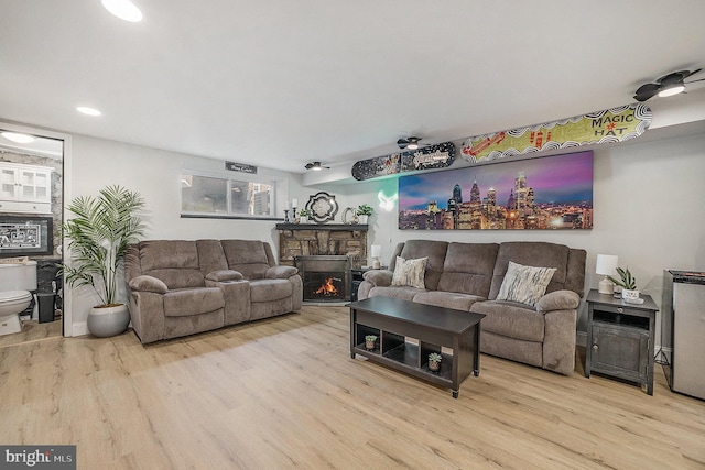 living area with a stone fireplace and wood finished floors