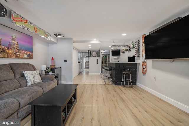 living room with recessed lighting, bar, baseboards, stairs, and light wood finished floors