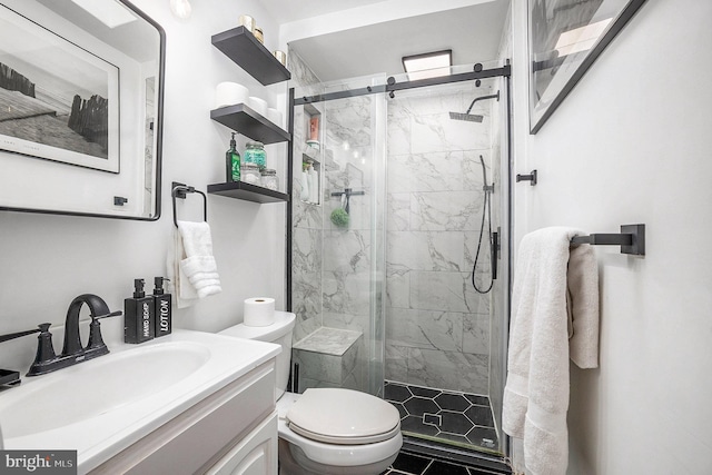 full bath with a marble finish shower, vanity, and toilet