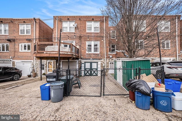 back of house with a gate, fence, and brick siding