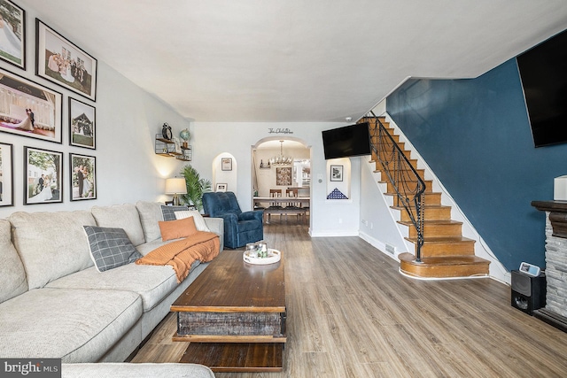 living room with baseboards, stairs, arched walkways, and wood finished floors