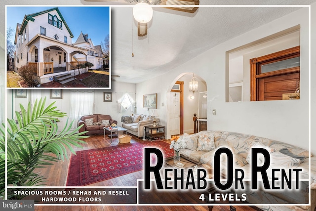 living area featuring a ceiling fan, arched walkways, and wood finished floors