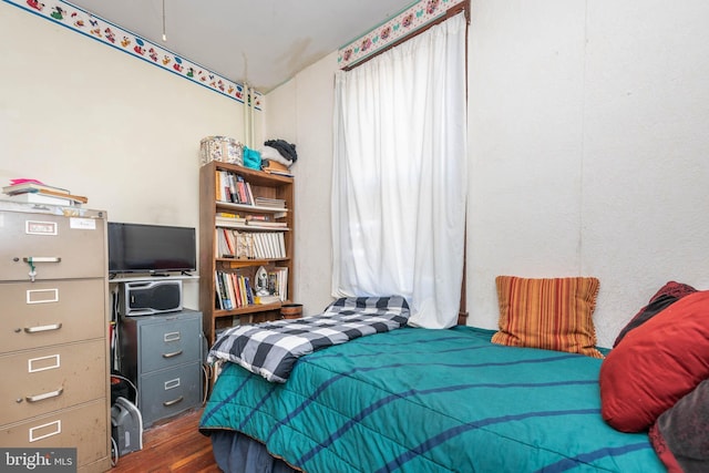 bedroom featuring multiple windows and dark wood-style flooring