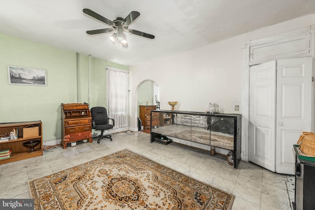 office with marble finish floor, baseboards, arched walkways, and a ceiling fan