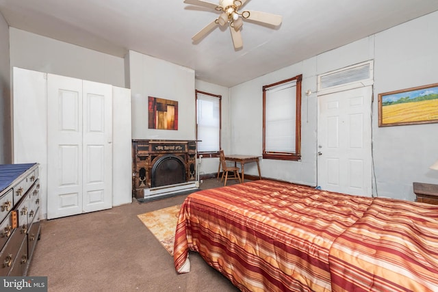 carpeted bedroom featuring a closet, a fireplace, and a ceiling fan