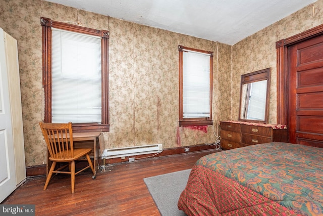 bedroom with baseboards, multiple windows, a baseboard heating unit, and hardwood / wood-style floors