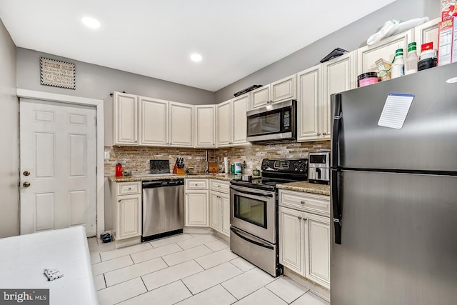 kitchen featuring light tile patterned floors, light stone counters, recessed lighting, appliances with stainless steel finishes, and backsplash