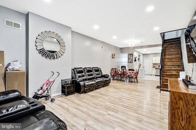 living room with light wood-style floors, recessed lighting, visible vents, and stairway