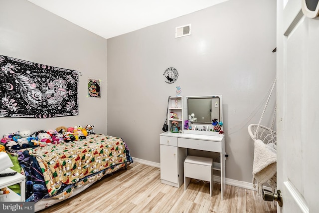 bedroom with wood finished floors, visible vents, and baseboards