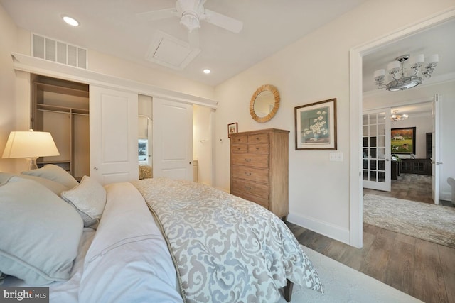 bedroom featuring wood finished floors, visible vents, baseboards, a closet, and attic access