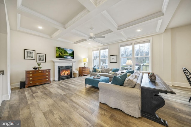 living area with a glass covered fireplace, coffered ceiling, beamed ceiling, and wood finished floors