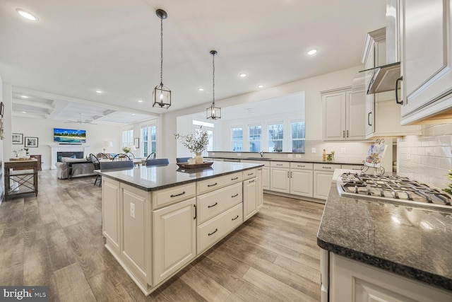 kitchen with decorative backsplash, light wood-style flooring, open floor plan, a fireplace, and a sink