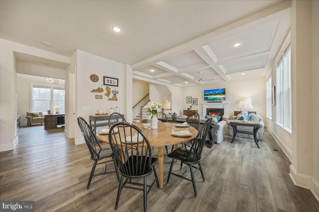 dining space with stairs, a lit fireplace, dark wood-style flooring, and coffered ceiling