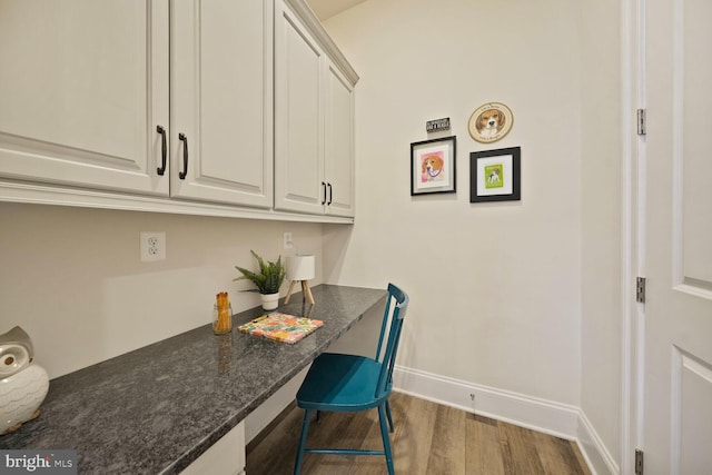 interior space featuring dark wood-style floors, built in desk, and baseboards