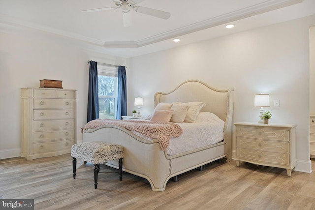 bedroom with ornamental molding, a tray ceiling, light wood finished floors, and recessed lighting