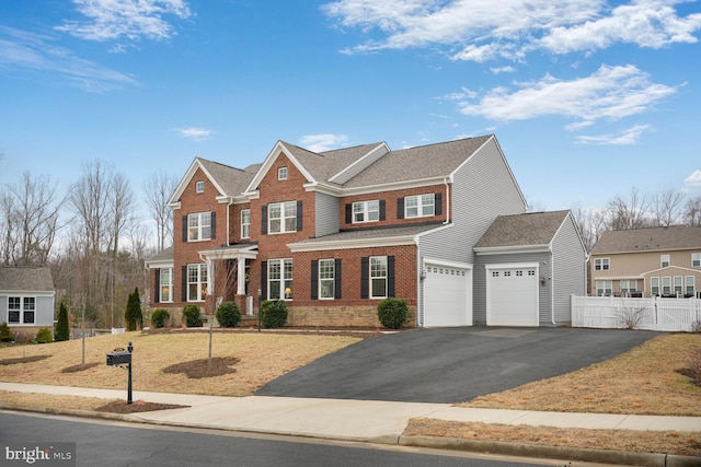 georgian-style home with a garage, brick siding, fence, and driveway